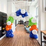 Customised Balloon arch with company's logo in blue, white, lime green and orange